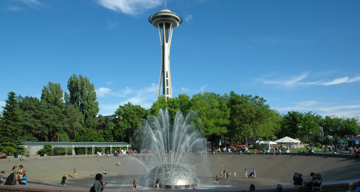 Families at the International Fountain at Seattle Center, one of the free things to do in Seattle with kids, with the Space Needle behind